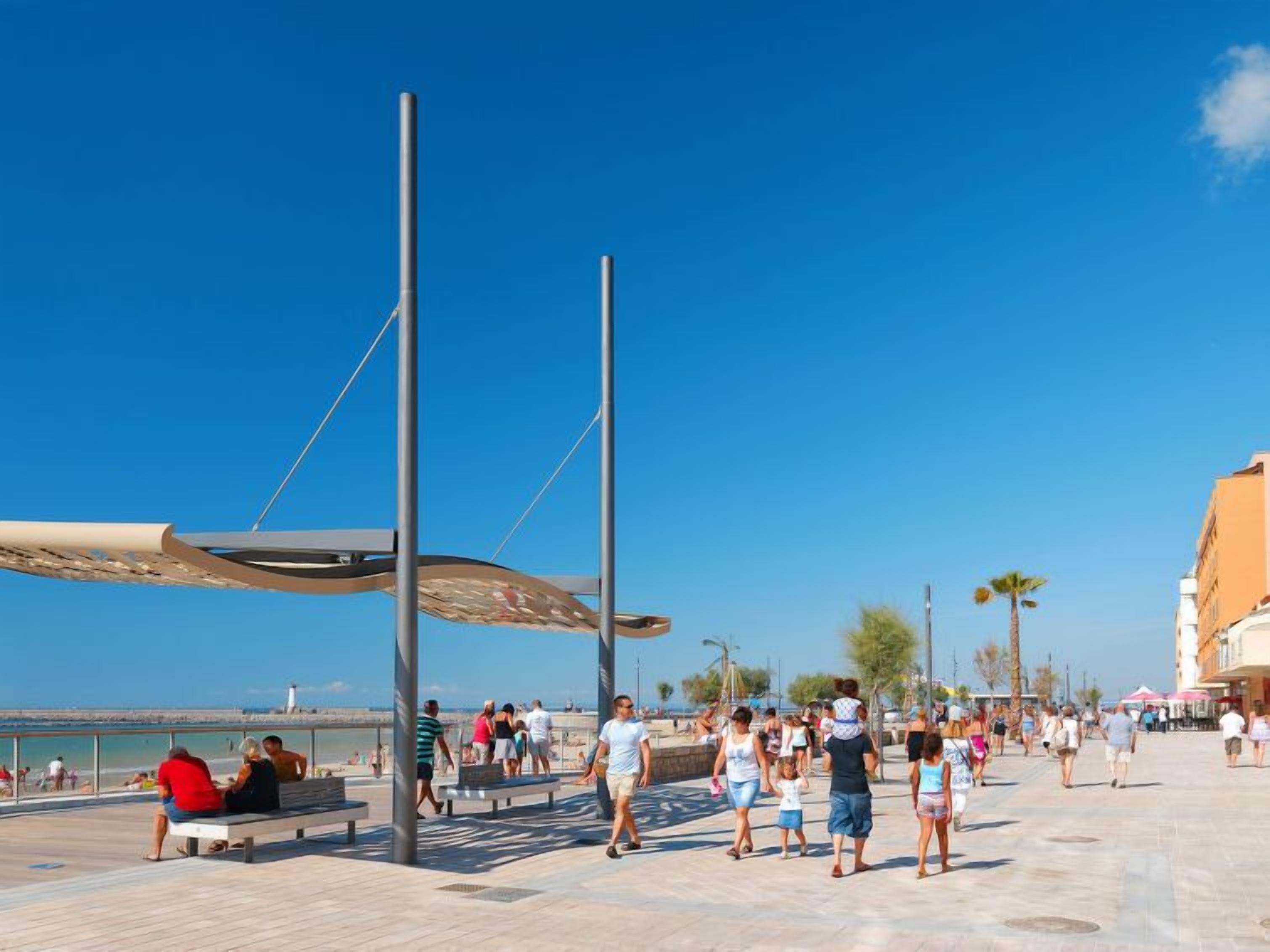 Eine Promenade mit Blick auf den Strand, Bänken und Spaziergängern.