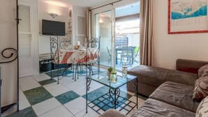 Una sala de estar con un sofá, una mesa de centro de vidrio y un comedor con mesa y sillas.