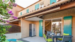 Un patio con mesa y sillas, un refrigerador y una zona cubierta con vista al interior.