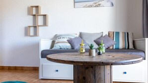 Ein gemütliches Zimmer mit einem Holztisch, einer Couch mit Kissen und einer kleinen Pflanze auf dem Tisch.