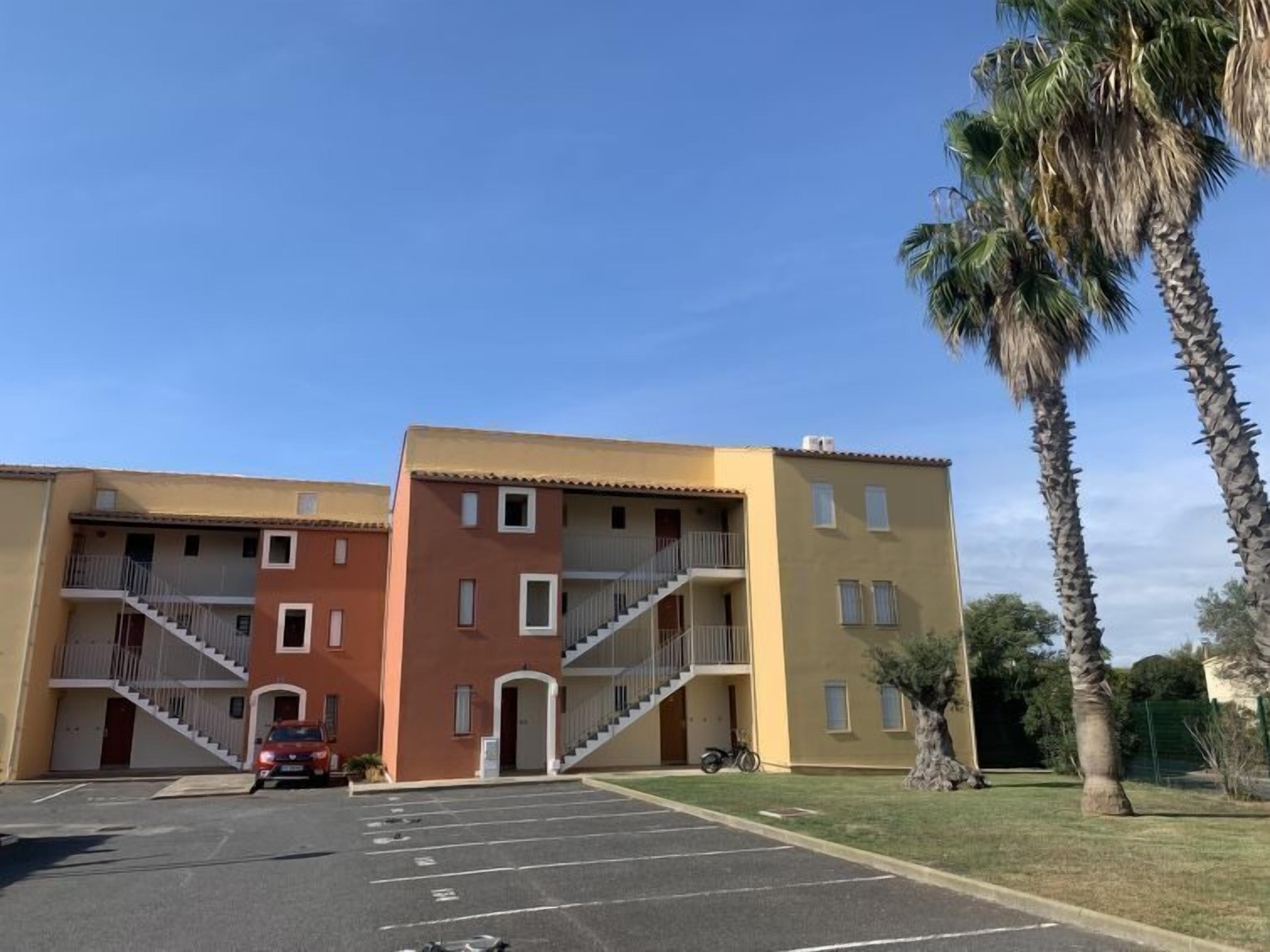 A multi-story building with a parking lot in front.