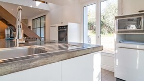 Una cocina moderna con un lavamanos de acero inoxidable, un horno empotrado y un microondas.