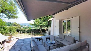 Un patio al aire libre con un sofá, mesa y sombrilla, con vistas a un paisaje pintoresco.