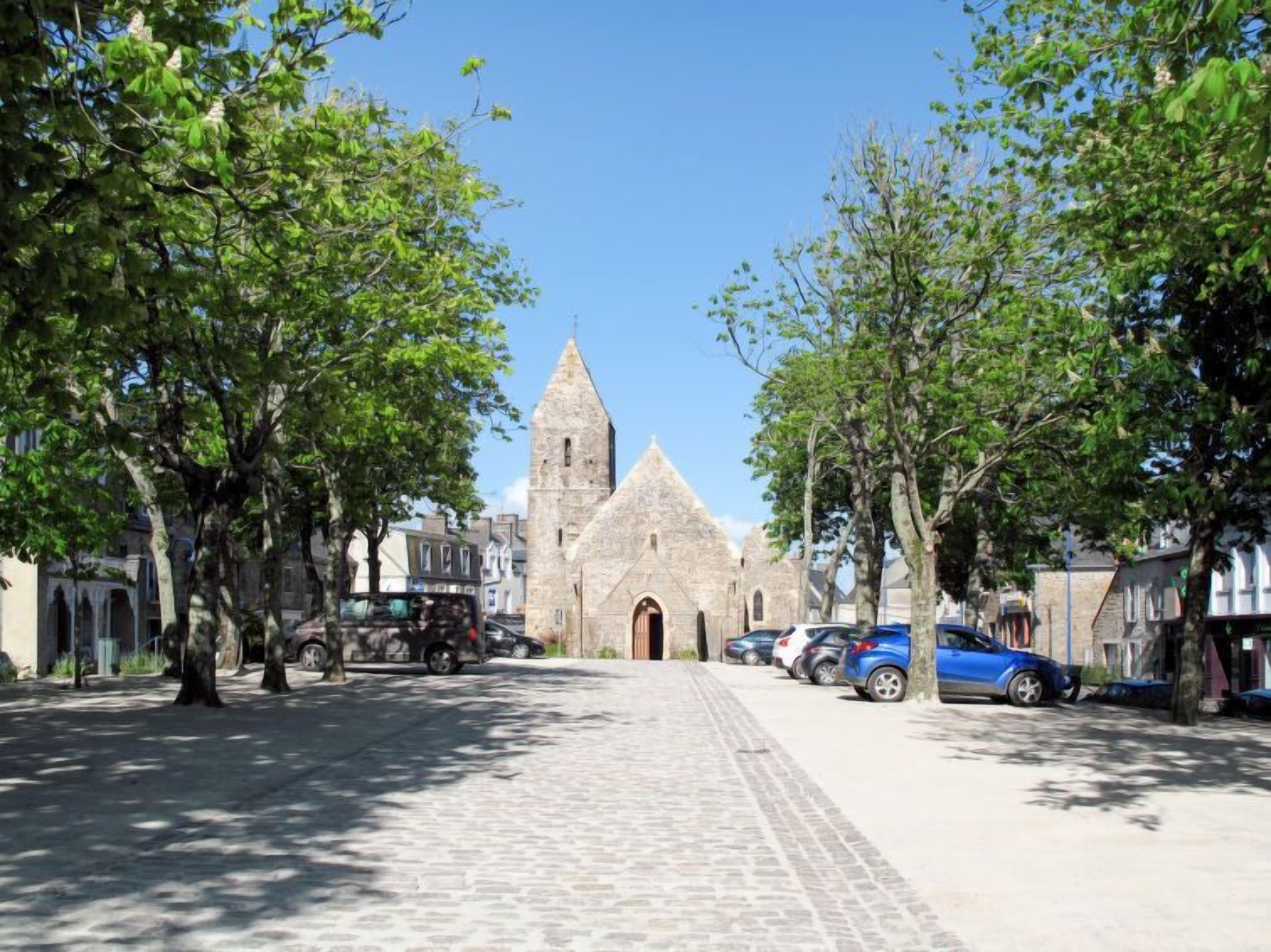 A cobblestone street leading to a historic church with a tall tower.