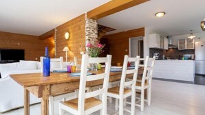 A modern kitchen with white cabinets, a wooden dining table, and a built-in oven. - La Plage by Interhome (Denneville)