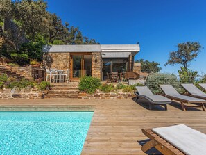 Et moderne hus med swimmingpool, stenvægge og udendørs møbler.