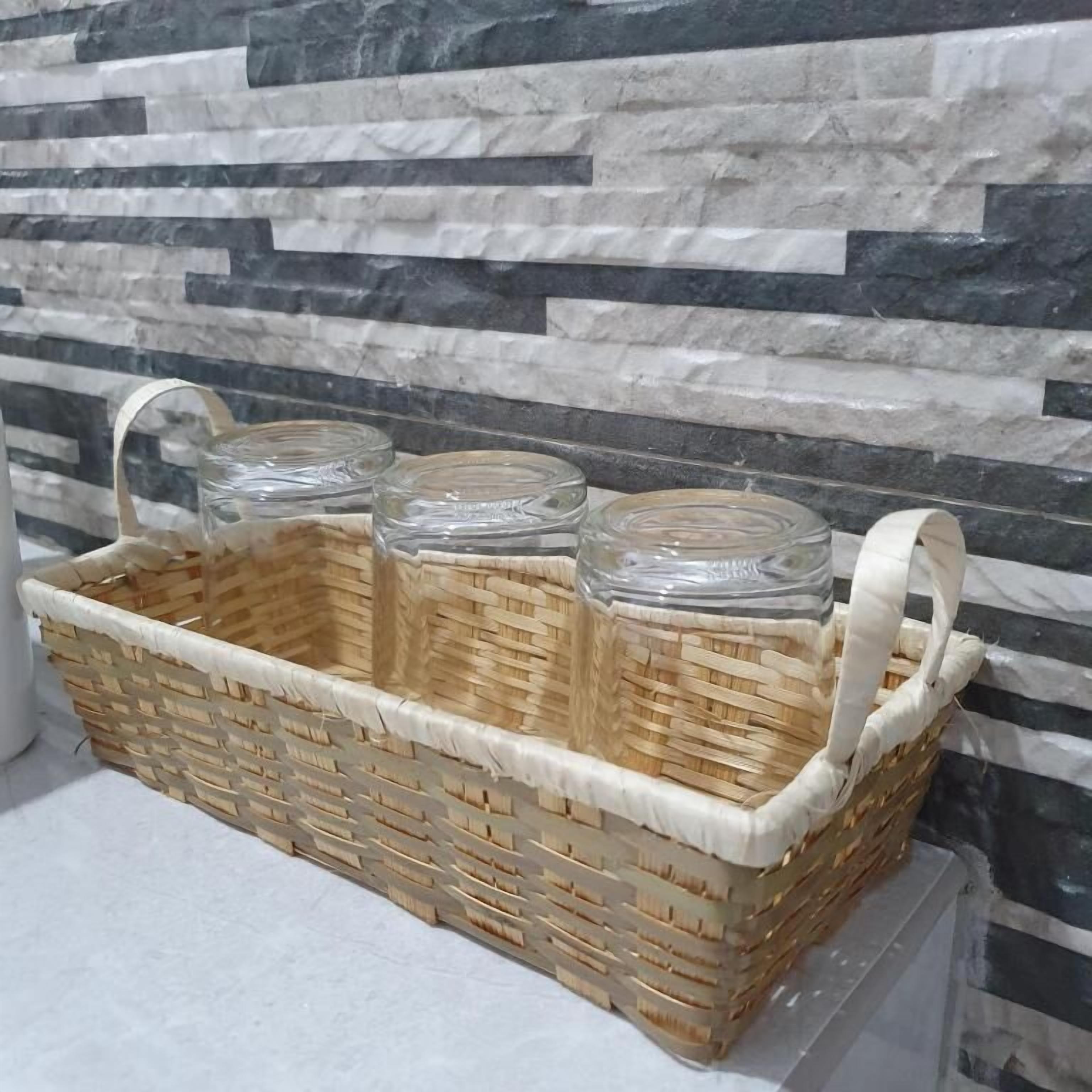 A woven basket with three glass jars on a white surface against a stone wall.