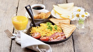 A breakfast plate with scrambled eggs, bacon, tomatoes, toast, and a glass of orange juice. - Chicago Motel (Jiaoxi)