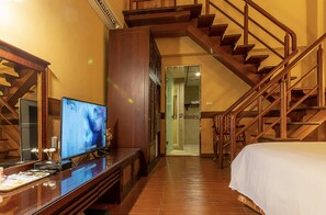 Ein Hotelzimmer mit einer Holztreppe, einem Fernseher auf einer Holzkabine und einem Bett mit weißer Bettdecke.