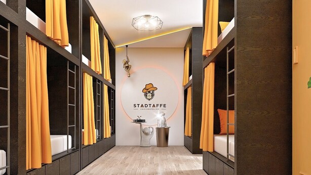 Un corridoio con pavimento in legno, tende gialle e un cartello appeso al muro per Stadtaffe Chic Hostel Vienna.