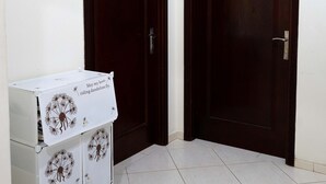 Een hoekzaal met twee donkerhouten deuren en een witte kast met leeuwendraden.