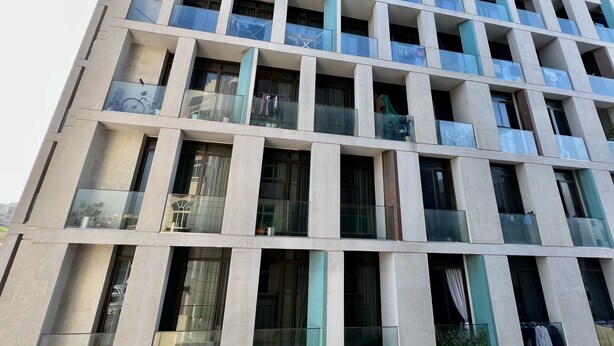 Een modern gebouw met een raster van balkons, grote ramen en een strak ontwerp.