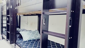 Een slaapkamer met stapelbedden, metalen spijlen en een witte muur.