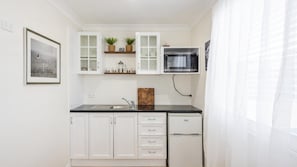 A compact kitchen with white cabinets, a microwave, and a sink.