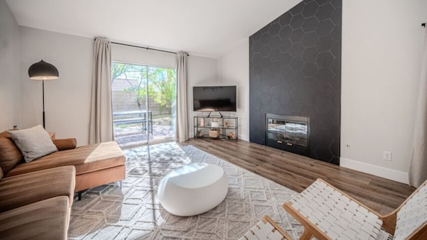 Una sala de estar moderna con sofá, reposapiés y chimenea.