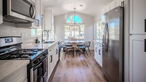 Una cocina moderna con armarios blancos, electrodomésticos de acero inoxidable y una mesa de comedor de madera.
