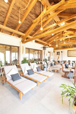 Una habitación soleada con vigas de madera, sillones de descanso y un amplio ventanal.