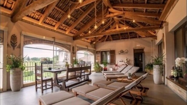Une pièce spacieuse avec un haut plafond en bois, un coin repas avec une table et des chaises, et une rangée de chaises longues.