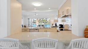Cocina moderna con una isla central, armarios blancos y vistas a una piscina.