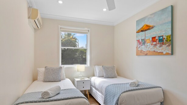 Une chambre avec deux lits, une fenêtre, un tableau et un appareil de climatisation.