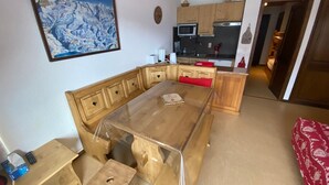 Una stanza con un tavolo da pranzo in legno, una cucina con mobili in legno e una mappa incorniciata appesa al muro.