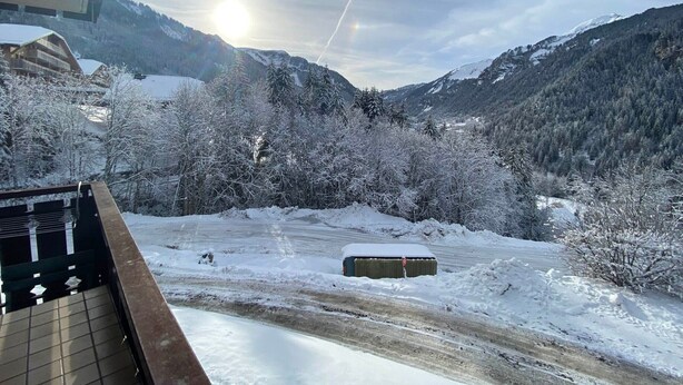 Paesaggio montuoso innevato con cielo sereno e un edificio in primo piano.