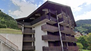 Un edificio a più piani con balconi, una scala e un’area parcheggio.