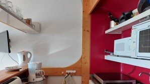 Ett kompakt kök med mikrovågsugn, brödrost, vattenkokare och en diskho.