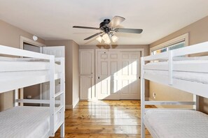A room with bunk beds, a ceiling fan, and a door with a light switch. - Bufflehead Cottage by Destination Big Bear: Pool Table! Spa! Mountain Views! (Big Bear City)