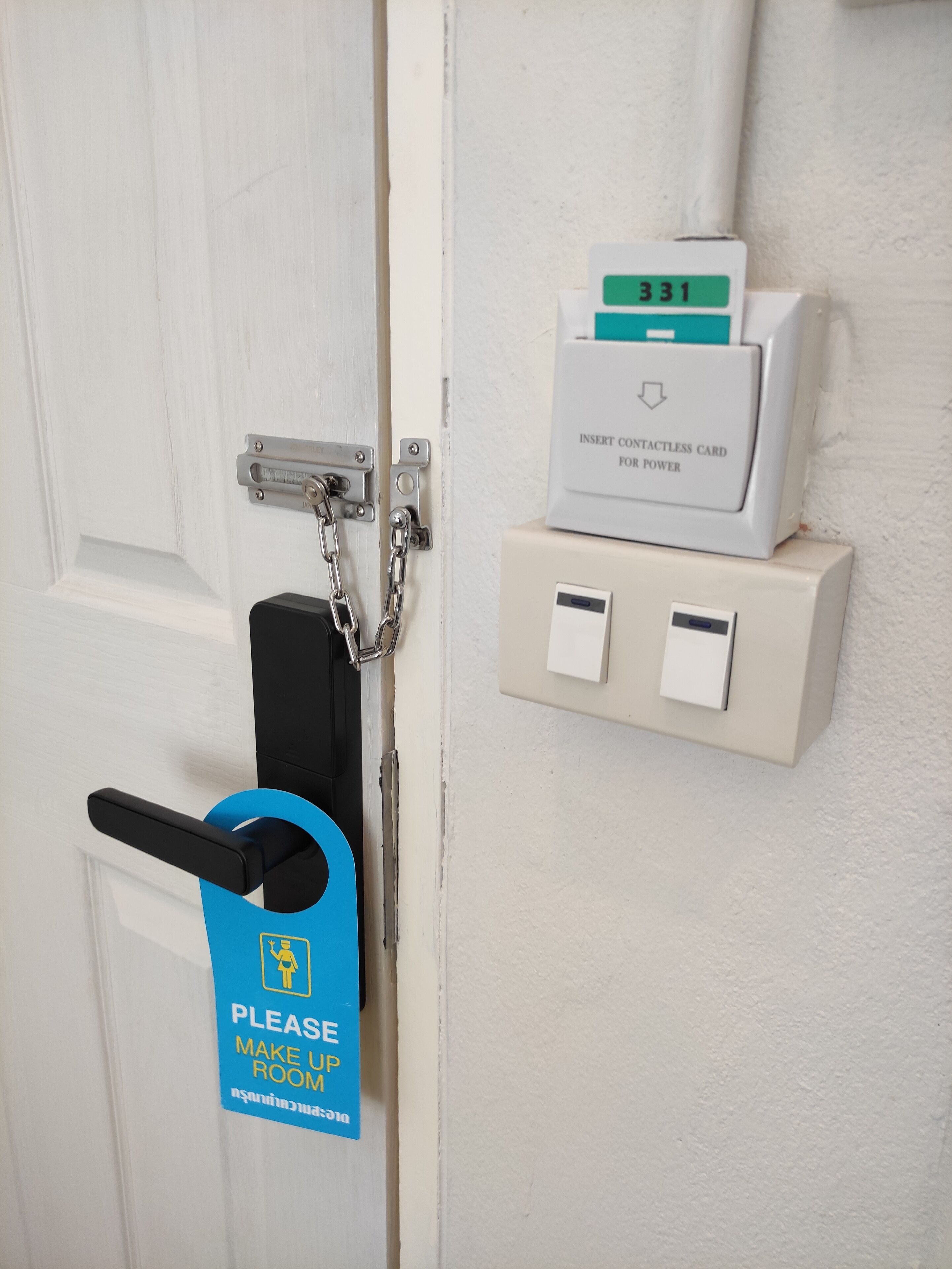 A door with a contactless card reader, a chain lock, and a sign instructing to make up the room.