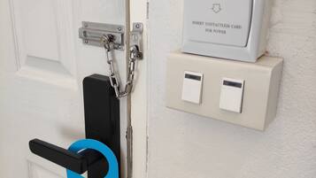 A door with a contactless card reader, a chain lock, and a sign instructing to make up the room.