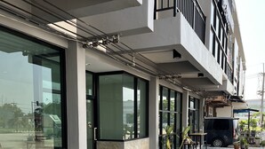 A modern building with large windows, a tiled walkway, and outdoor seating.
