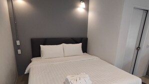 Ett modernt hotellrum med en stor säng, två sänglampor och en prydligt bäddad säng med en hopvikt handduk.
