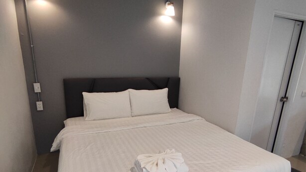 A modern hotel room with a large bed, two bedside lamps, and a neatly made bed with a folded towel.