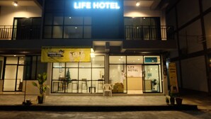 En byggnad med en skylt där det står ”LIFE HOTEL” och en gul banner som annonserar ett program för barn.