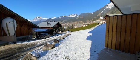 A snowy mountain road with buildings and a clear blue sky.