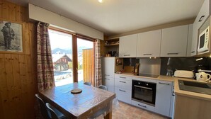 Une cuisine équipée d’une table à manger, de chaises, de placards, d’un four à micro-ondes et d’un four traditionnel.