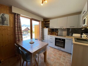 Une cuisine équipée d’une table à manger, de chaises, de placards, d’un four à micro-ondes et d’un four traditionnel.