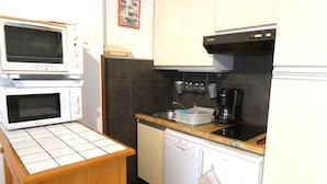 Cocina compacta equipada con microondas, cafetera y lavavajillas pequeño.