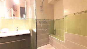 Un baño con cabina de ducha de vidrio, un lavamanos blanco y un espejo.