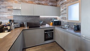 A modern kitchen with a stone wall backsplash, integrated appliances, and a built-in oven. - Prestigious chalet with jacuzzi - 10 guests (Courchevel 1550)