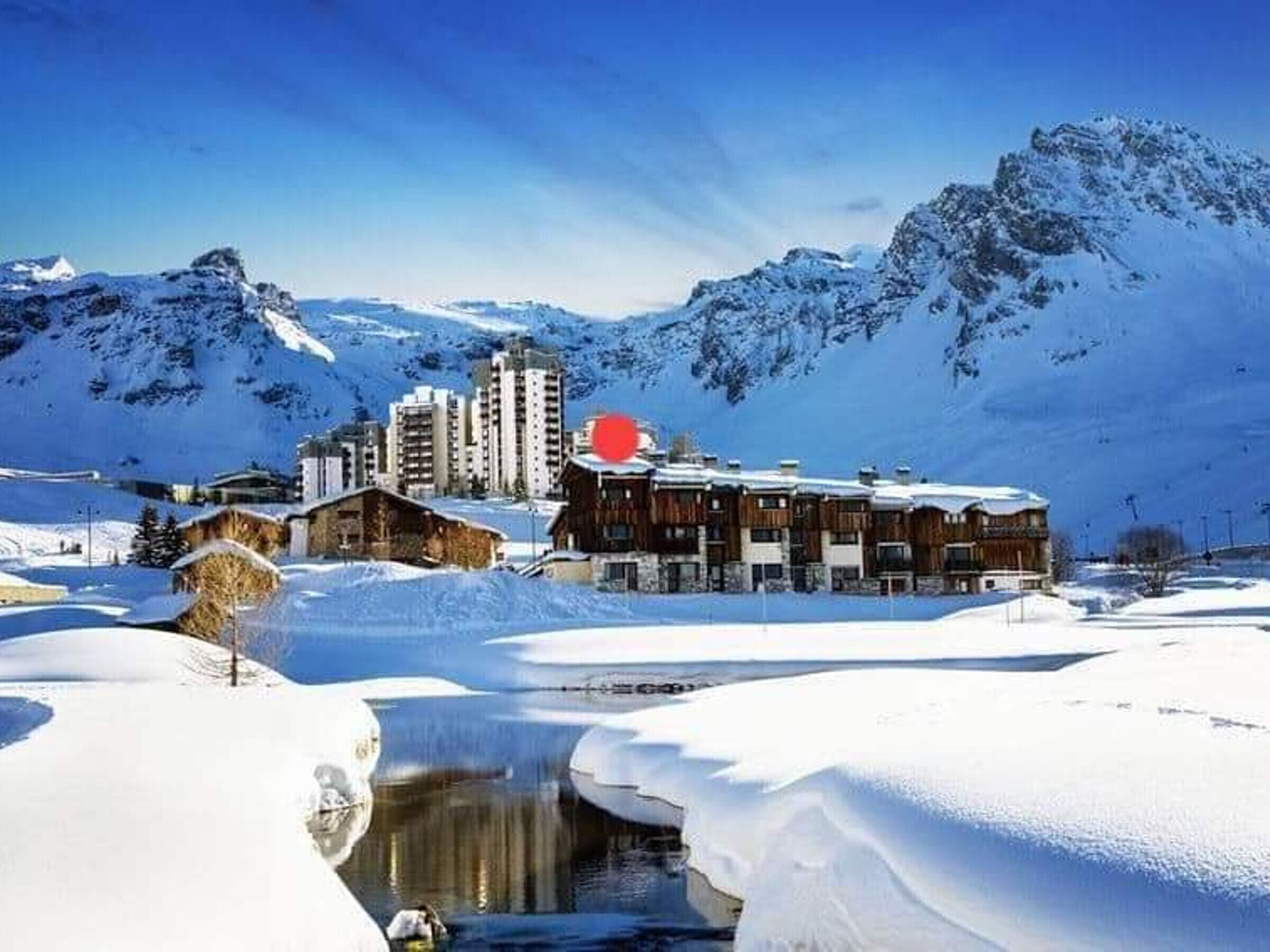 A snow-covered mountain resort with wooden buildings and a ski lift.