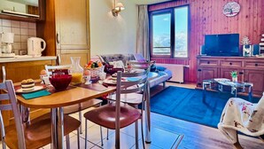 Een gezellige keuken met houten kasten, een eettafel met stoelen, een bank en een televisie.