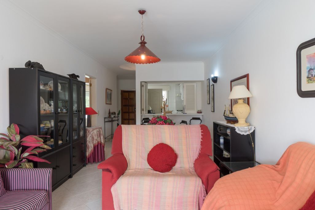 Un salon avec un canapé à rayures, un fauteuil rouge, un meuble et une lampe suspendue.