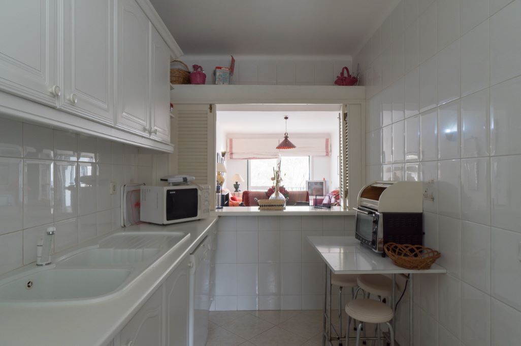 A compact kitchen with white cabinets, a microwave, a toaster, and a sink.