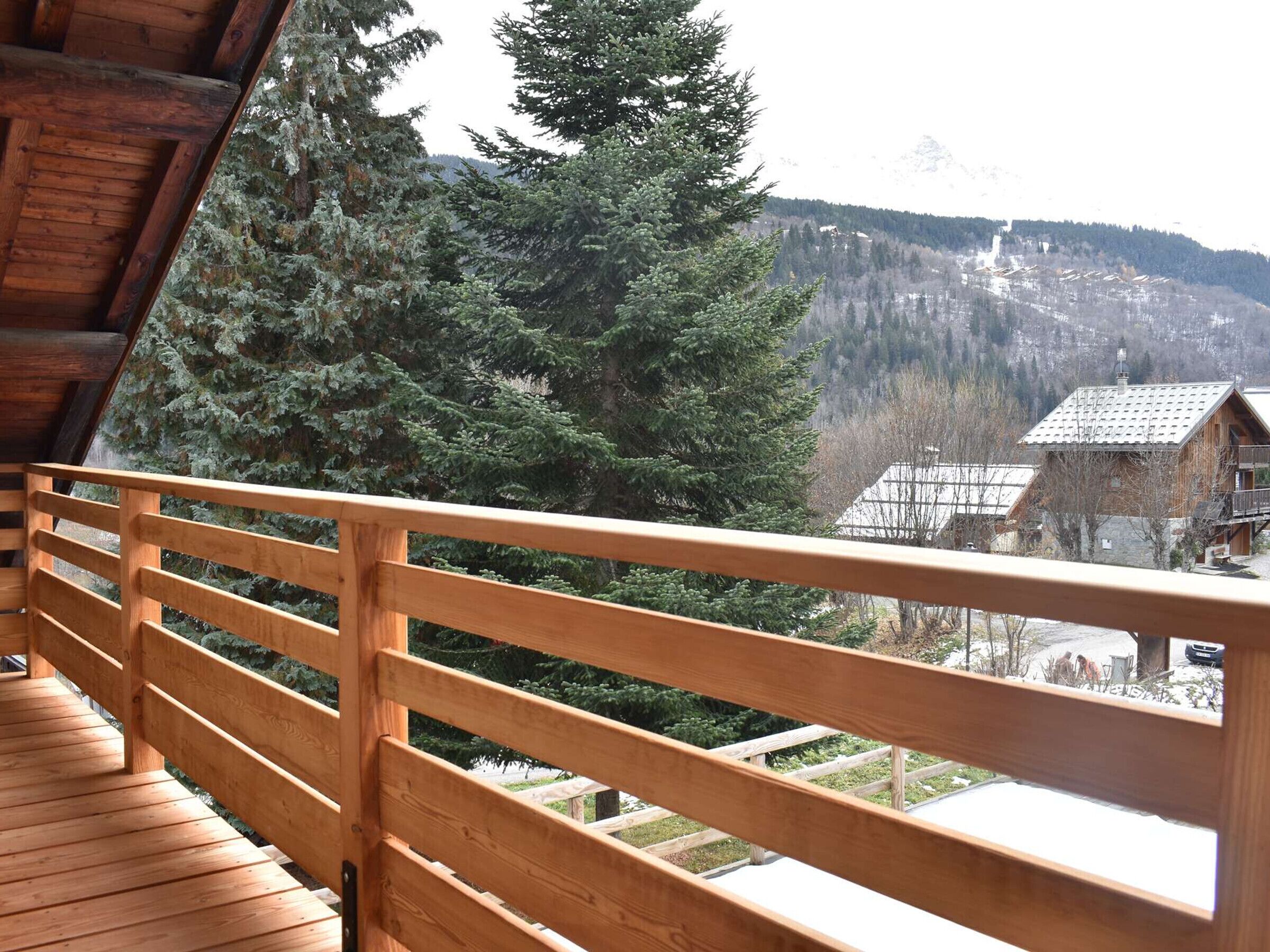 A wooden balcony with a view of a mountainous landscape and a cabin.