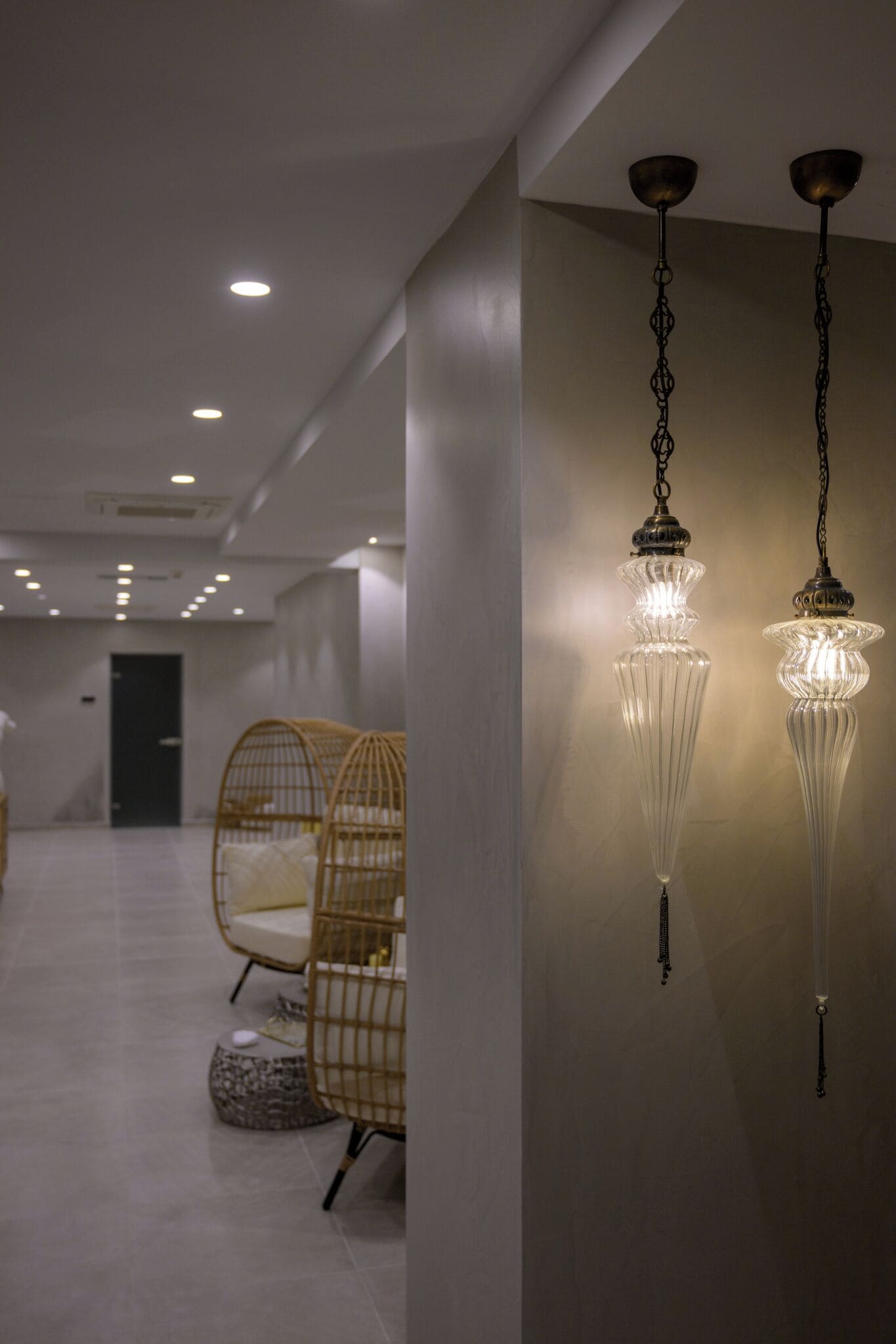 Un intérieur moderne agrémenté de lustres en cristal suspendus, de chaises en osier et d’une palette de couleurs neutres.