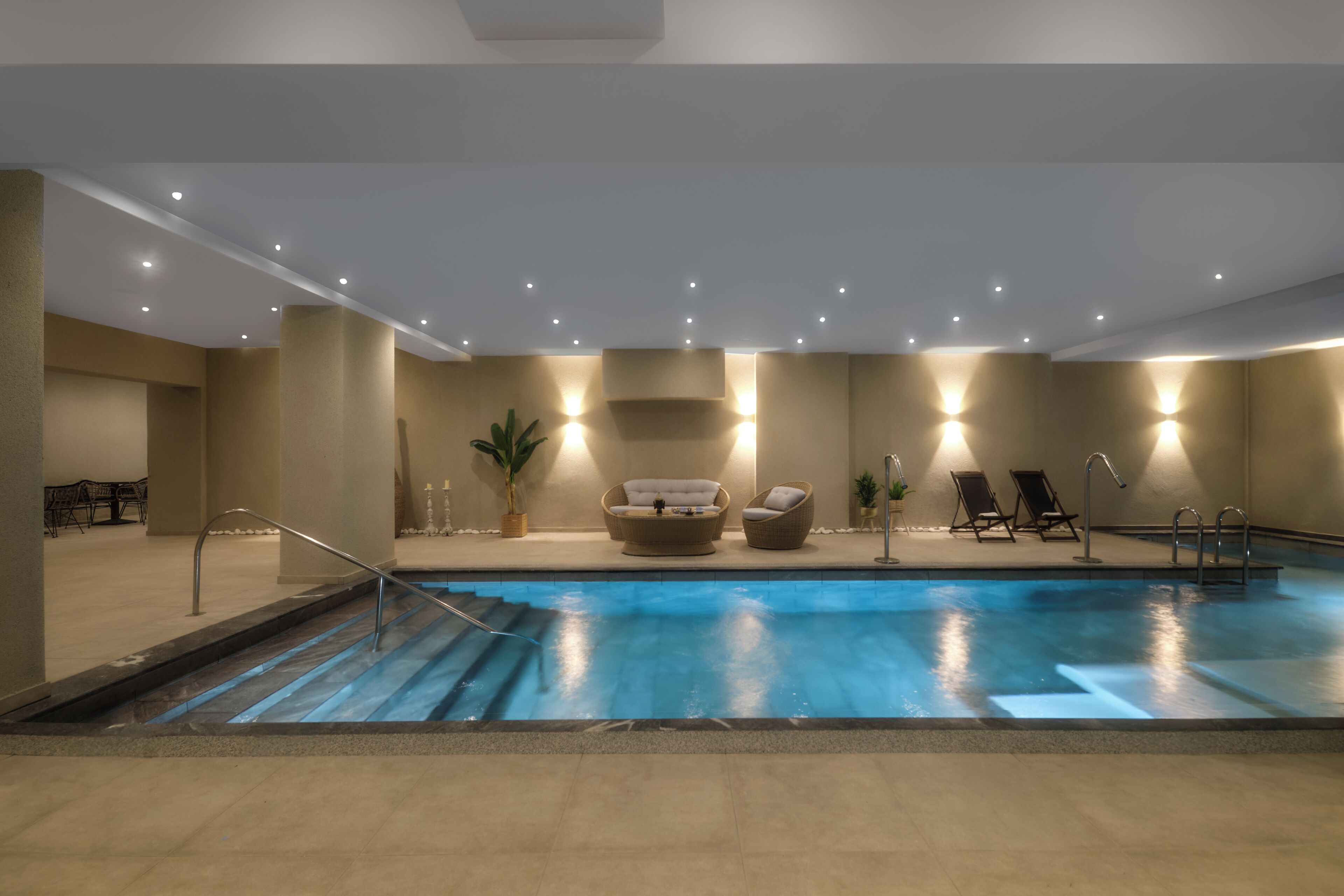 Una piscina con una zona de estar hundida, un pequeño espacio de descanso junto a la piscina y una escalera de acceso a la piscina.