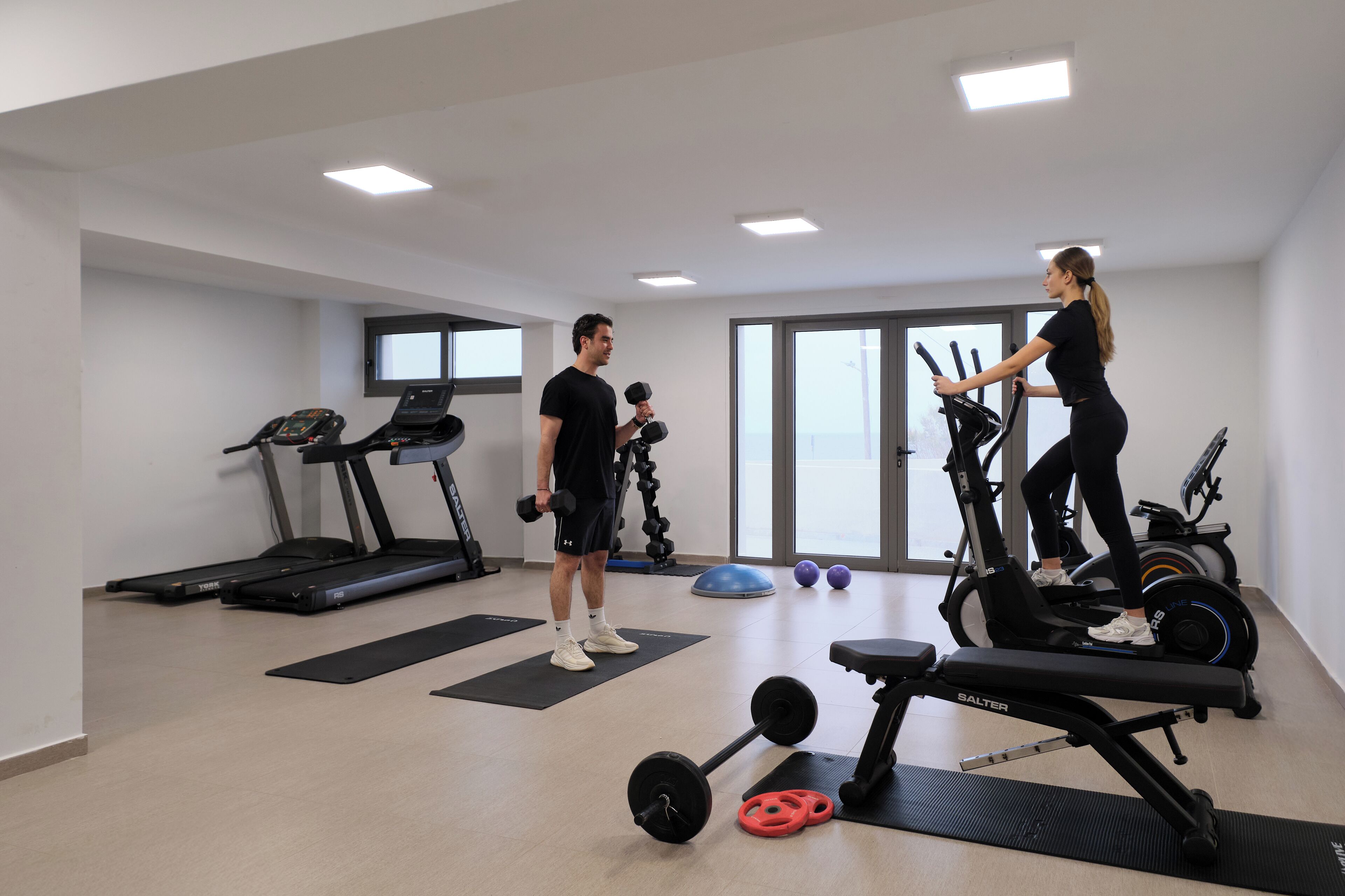 Un gimnasio con cintas de correr, elípticas y pesas sueltas.