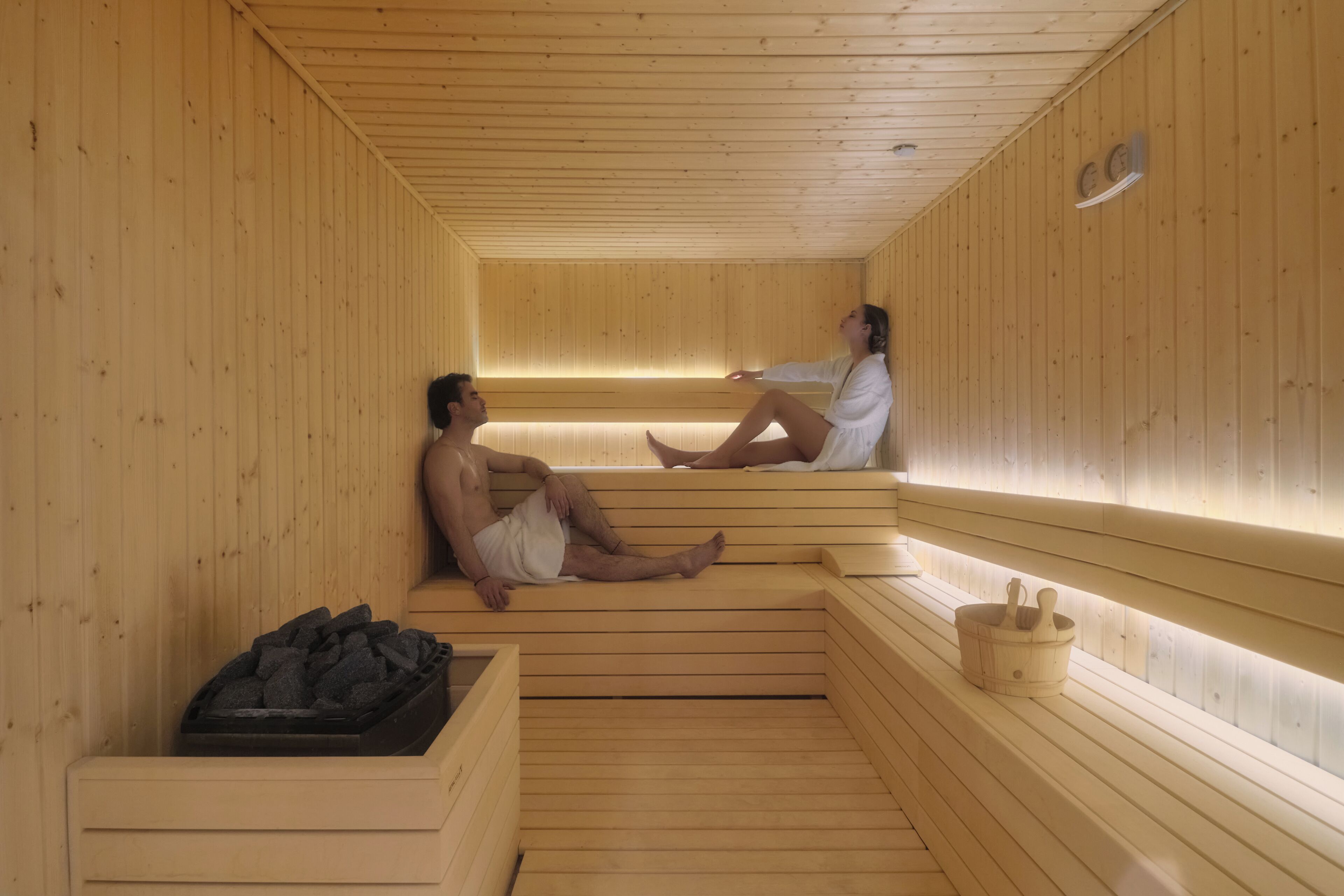 Una sauna con bancos de madera y un calentador de piedra.
